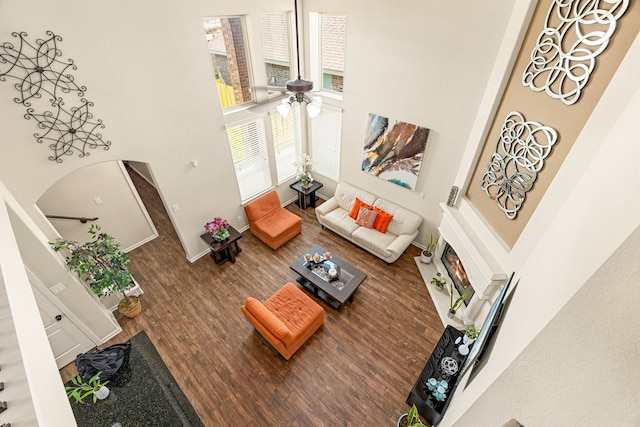 living area featuring a towering ceiling, ceiling fan, wood finished floors, and arched walkways