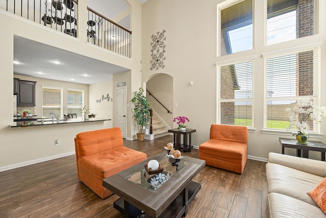 living room with baseboards, dark wood-style floors, a towering ceiling, and stairway