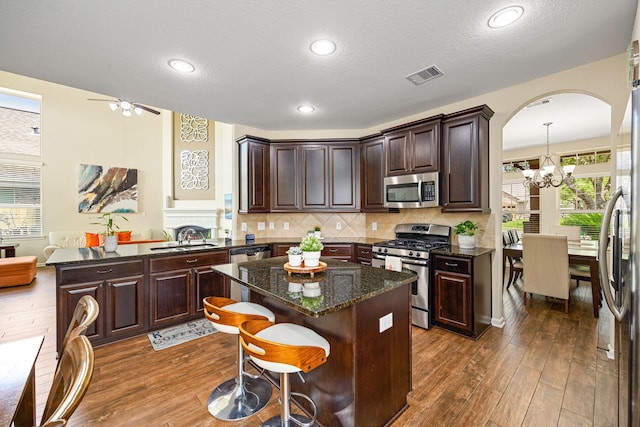 kitchen with stainless steel appliances, a chandelier, a peninsula, a sink, and dark wood finished floors
