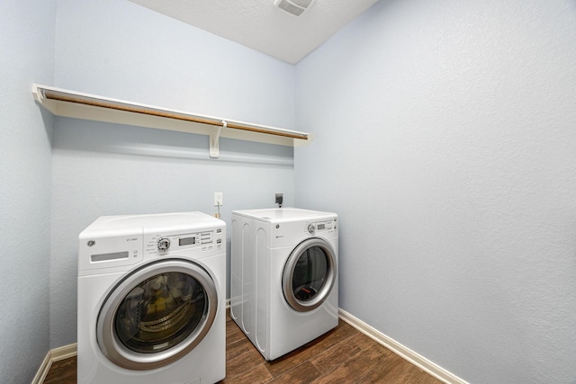 laundry area featuring washer and clothes dryer, dark wood-type flooring, and baseboards