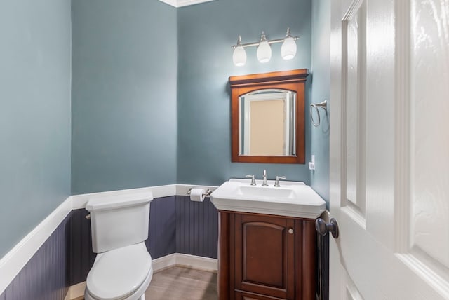 44 Logansport Ct, Montgomery, TX 77356 - bathroom featuring toilet, vanity, wainscoting, and wood finished floors