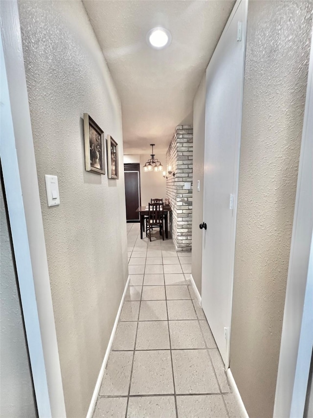 2016 Main St Unit Ph3, Houston, TX 77002 - hallway featuring baseboards, a chandelier, a textured wall, and light tile patterned floors