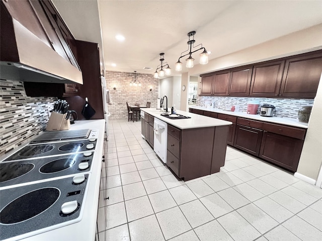 2016 Main St Unit Ph3, Houston, TX 77002 - kitchen with under cabinet range hood, light tile patterned floors, a kitchen island with sink, light countertops, and decorative backsplash