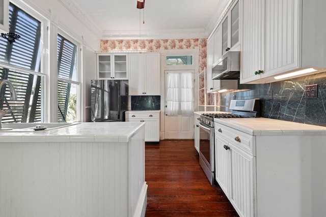 1827 Ball St, Galveston, TX 77550 - kitchen featuring stainless steel gas range, freestanding refrigerator, tile countertops, ornamental molding, and glass insert cabinets