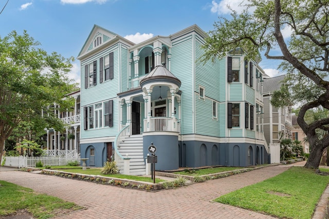 1827 Ball St, Galveston, TX 77550 - view of front facade featuring covered porch, decorative driveway, stairway, and stucco siding