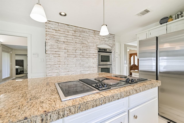 4734 Baywood Dr, Pasadena, TX 77505 - kitchen featuring appliances with stainless steel finishes, white cabinetry, brick wall, and pendant lighting