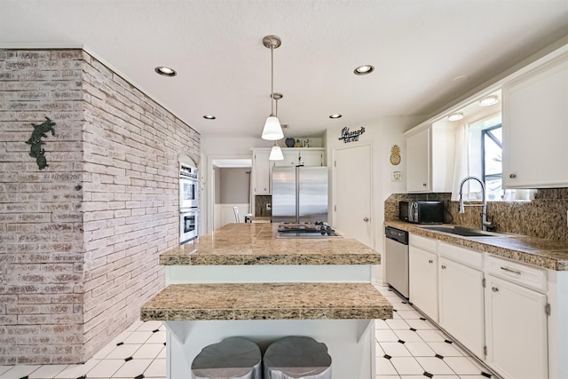 4734 Baywood Dr, Pasadena, TX 77505 - kitchen featuring brick wall, stainless steel appliances, a sink, a kitchen island, and plenty of natural light