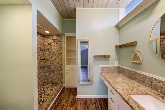 full bathroom featuring wood finished floors, a tile shower, vanity, wooden ceiling, and baseboards