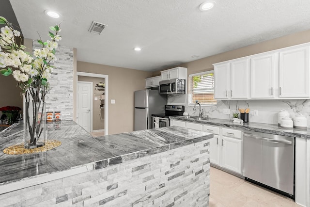 6719 Woodland Oaks, Magnolia, TX 77354 - kitchen featuring appliances with stainless steel finishes, dark stone counters, a sink, white cabinetry, and recessed lighting