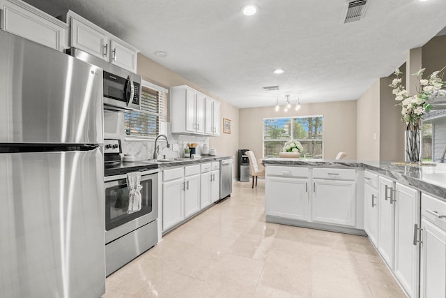 6719 Woodland Oaks, Magnolia, TX 77354 - kitchen with stainless steel appliances, a sink, white cabinetry, recessed lighting, and tasteful backsplash