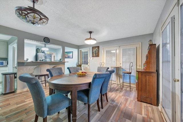 7027 Iowa Colony Blvd, Rosharon, TX 77583 - dining space with french doors, a textured ceiling, and light wood-type flooring