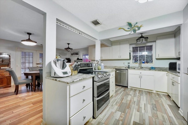 7027 Iowa Colony Blvd, Rosharon, TX 77583 - kitchen featuring appliances with stainless steel finishes, light wood-style flooring, white cabinets, a sink, and light stone counters