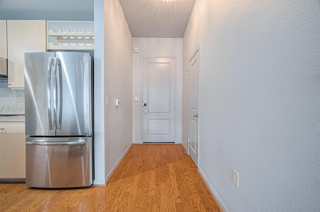 corridor featuring light wood-type flooring and baseboards