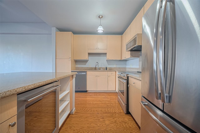 kitchen with appliances with stainless steel finishes, beverage cooler, a sink, light wood-style floors, and cream cabinetry