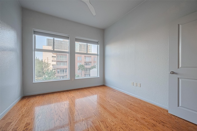 empty room with light wood-style flooring, baseboards, and a ceiling fan