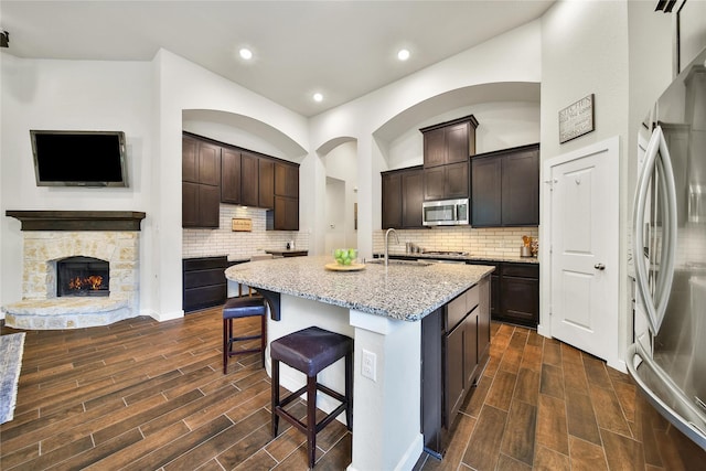 16711 Ramsay Cascades Dr, Humble, TX 77346 - kitchen with stainless steel appliances, wood tiled floors, light stone counters, a kitchen breakfast bar, and recessed lighting
