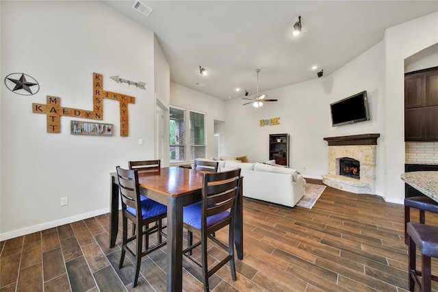 16711 Ramsay Cascades Dr, Humble, TX 77346 - dining space featuring ceiling fan, dark wood-style floors, a stone fireplace, baseboards, and lofted ceiling