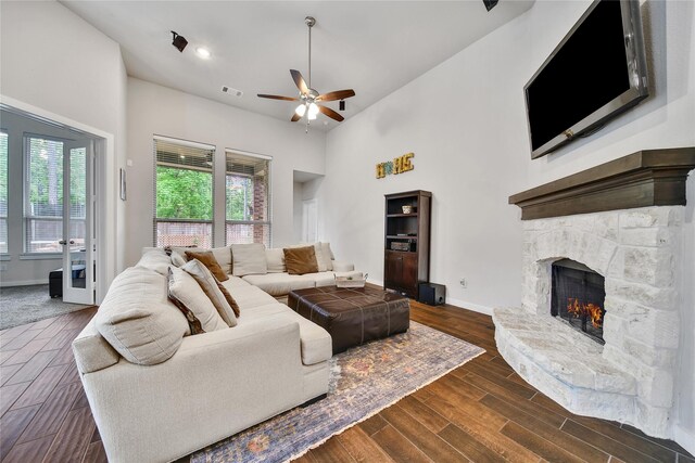 16711 Ramsay Cascades Dr, Humble, TX 77346 - living area with a stone fireplace, ceiling fan, baseboards, dark wood finished floors, and a towering ceiling