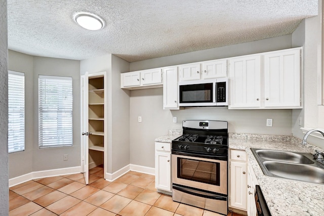 4319 Conward Dr, Houston, TX 77066 - kitchen featuring white microwave, stainless steel range with gas stovetop, a sink, white cabinets, and light countertops