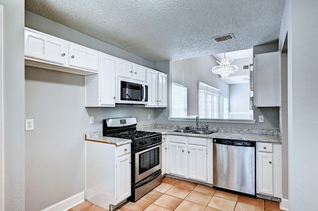 4319 Conward Dr, Houston, TX 77066 - kitchen featuring stainless steel appliances, a sink, white cabinets, a chandelier, and a textured ceiling