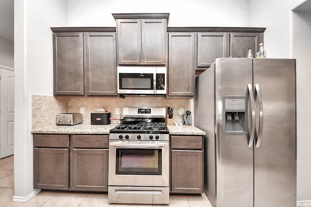 4827 San Gregorio Ln, Katy, TX 77493 - kitchen featuring stainless steel appliances, light tile patterned floors, backsplash, and dark brown cabinetry