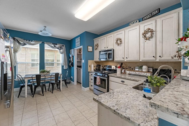 8315 Egret Bay Cir, Baytown, TX 77523 - kitchen with stainless steel appliances, baseboards, light tile patterned floors, light stone countertops, and white cabinets