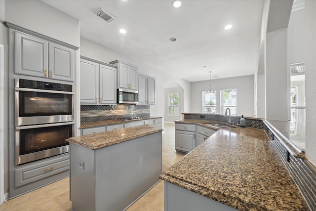 11127 Salento Ct, Richmond, TX 77406 - kitchen with a sink, stainless steel appliances, gray cabinets, arched walkways, and backsplash