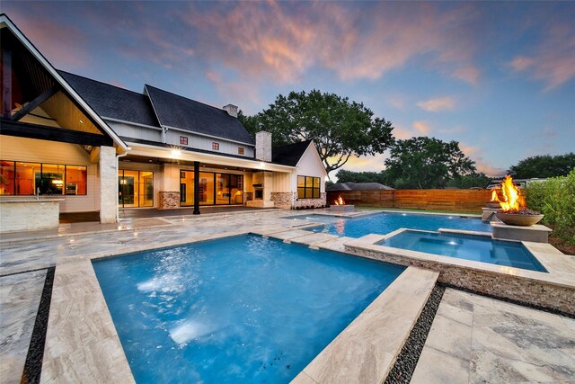 18829 Cypress Church Rd, Cypress, TX 77433 - pool at dusk with a fire pit, a patio, a fenced backyard, and a pool with connected hot tub