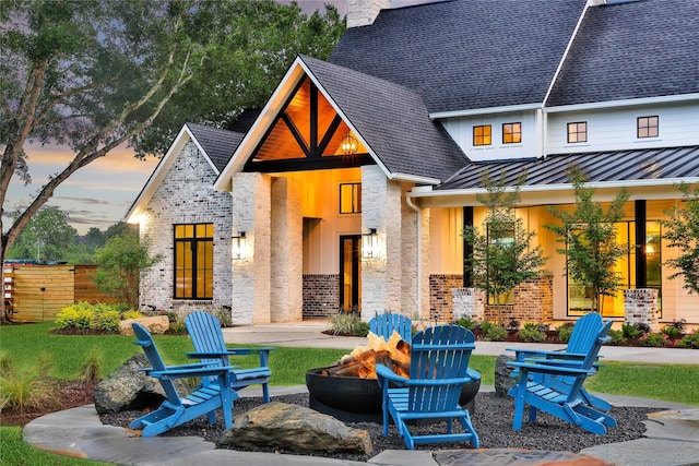 18829 Cypress Church Rd, Cypress, TX 77433 - back of house with a fire pit, a standing seam roof, roof with shingles, metal roof, and brick siding