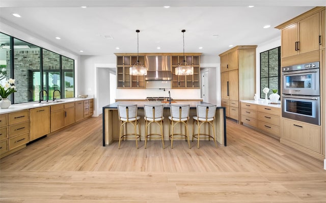 18829 Cypress Church Rd, Cypress, TX 77433 - kitchen with wall chimney range hood, stainless steel double oven, glass insert cabinets, light wood-style floors, and light countertops