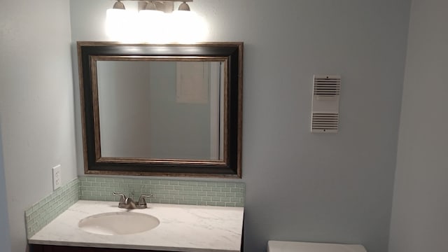 bathroom with decorative backsplash, toilet, and vanity