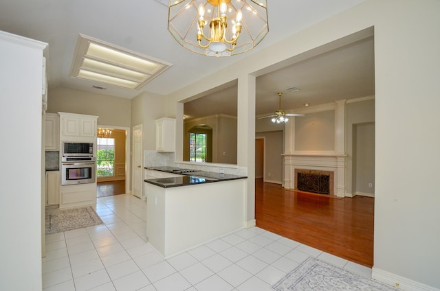 2303 Reflection Ct, Missouri City, TX 77459 - kitchen featuring appliances with stainless steel finishes, light tile patterned floors, decorative backsplash, a fireplace with flush hearth, and a chandelier