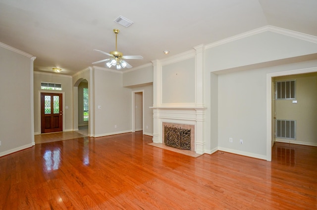 2303 Reflection Ct, Missouri City, TX 77459 - unfurnished living room featuring wood finished floors, ceiling fan, a fireplace with flush hearth, arched walkways, and ornamental molding