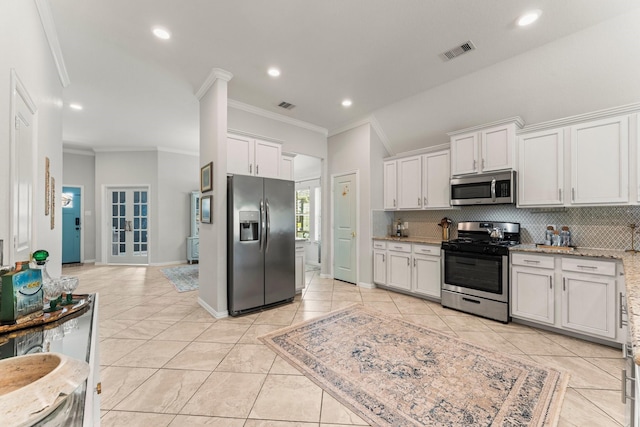 kitchen featuring stainless steel appliances, decorative backsplash, crown molding, white cabinetry, and light stone counters