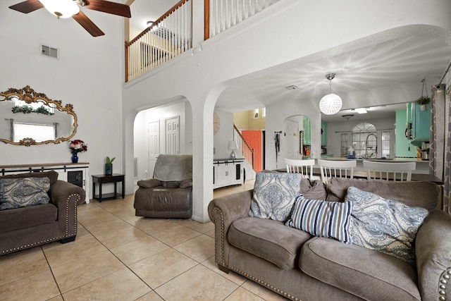 405 Spencer Lndg W, La Porte, TX 77571 - living room featuring arched walkways, a ceiling fan, light tile patterned floors, a high ceiling, and baseboards