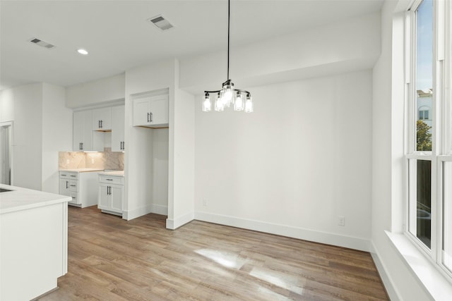 unfurnished dining area featuring light wood-style flooring, a chandelier, recessed lighting, and baseboards
