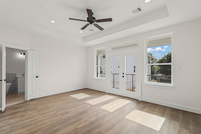 unfurnished bedroom featuring a raised ceiling, light wood-style flooring, french doors, baseboards, and recessed lighting