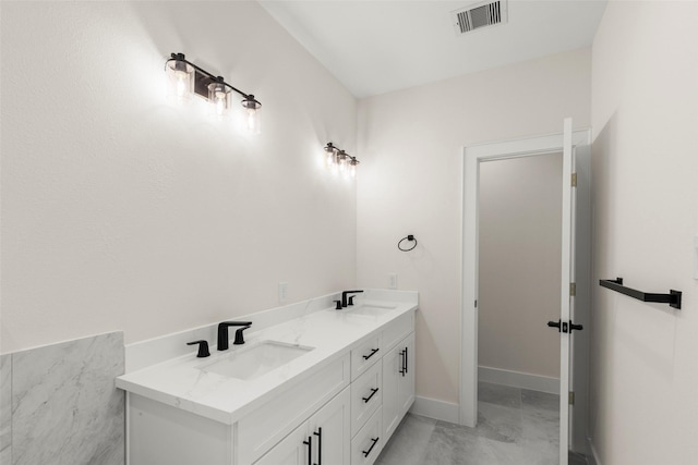 bathroom with marble look tile flooring, baseboards, and double vanity
