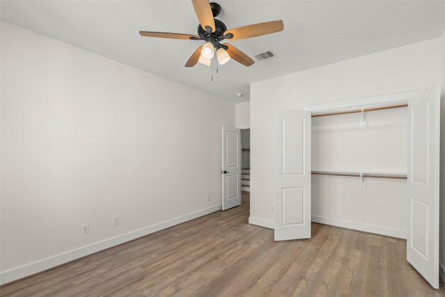 unfurnished bedroom featuring wood finished floors, a closet, baseboards, and a ceiling fan