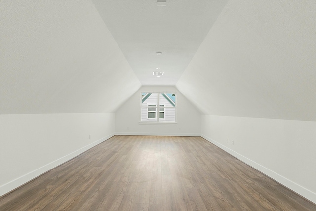 bonus room with wood finished floors, baseboards, and vaulted ceiling