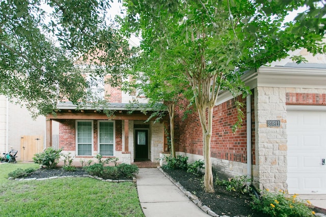 view of front of home with a front lawn, brick siding, an attached garage, and a porch
