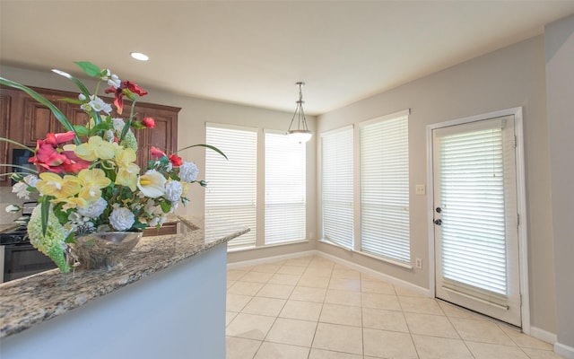 unfurnished dining area featuring baseboards, light tile patterned flooring, plenty of natural light, and recessed lighting