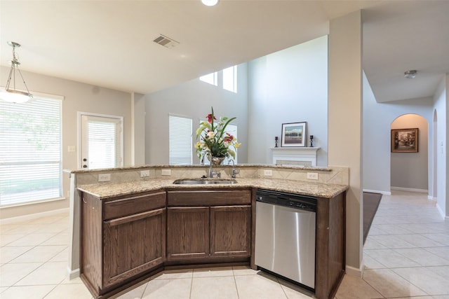 kitchen featuring dishwasher, a sink, arched walkways, and light tile patterned flooring