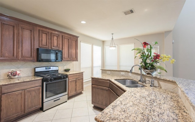 kitchen with black microwave, stainless steel gas stove, a sink, backsplash, and light tile patterned floors