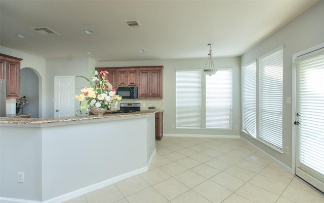 kitchen featuring black microwave, gas stove, baseboards, arched walkways, and light stone counters
