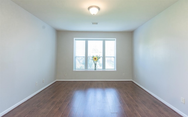 unfurnished room featuring baseboards and dark wood-style flooring