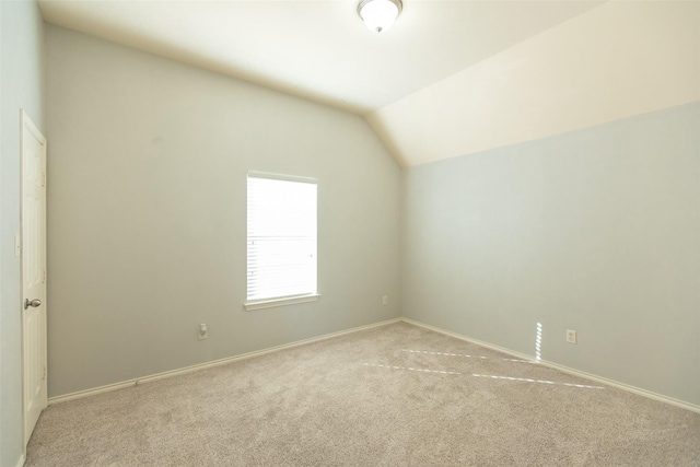 spare room with carpet flooring, vaulted ceiling, and baseboards