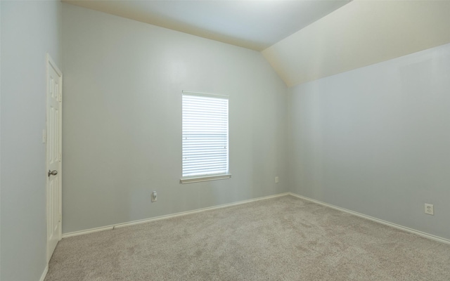 spare room with carpet floors, vaulted ceiling, and baseboards