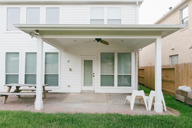 entrance to property featuring a ceiling fan, fence, and a patio area