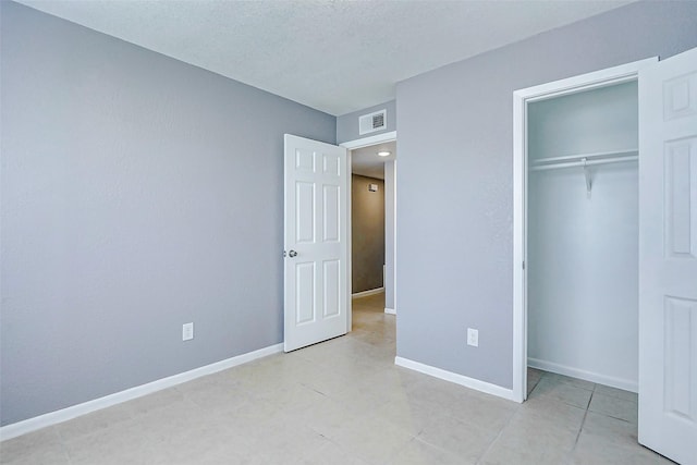 742 Pine Ave, Hempstead, TX 77445 - unfurnished bedroom featuring light tile patterned floors, a closet, baseboards, and a textured ceiling